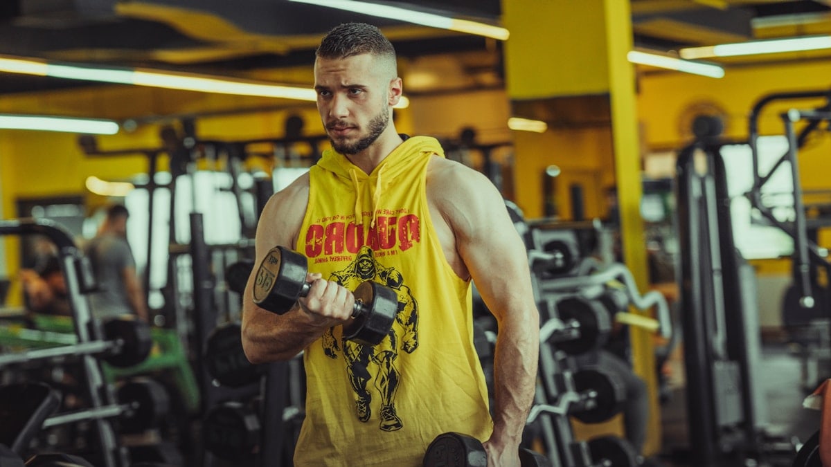 a man in a gym holding a pair of dumbs